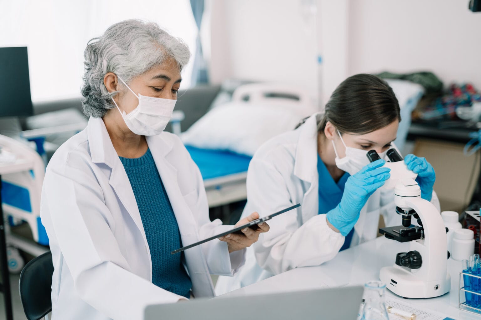Team of biochemical research scientists working with a microscope for vaccine development in pharmaceutical research labeling.